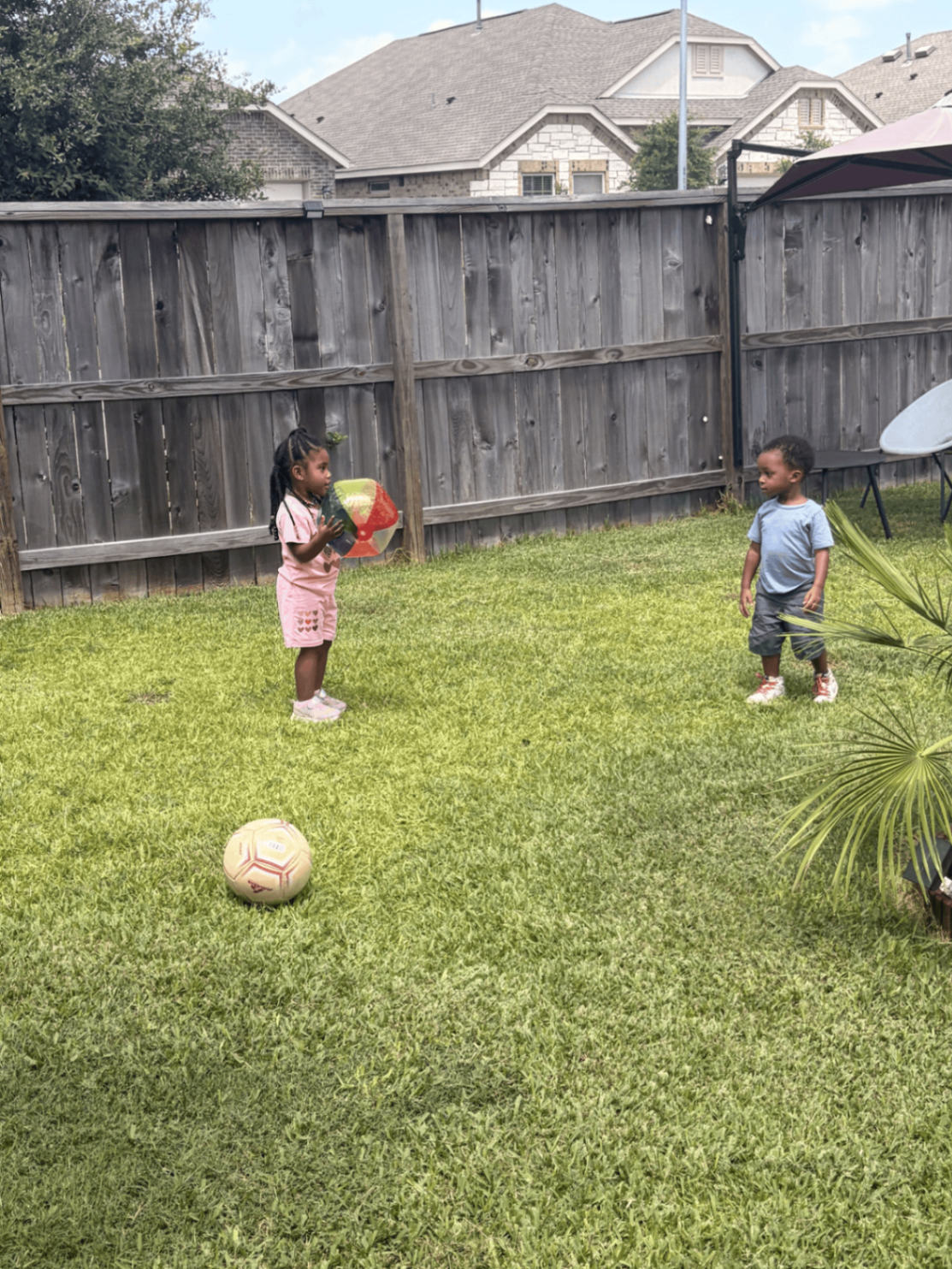 Preschoolers playing ball outdoors during movement time in the backyard play area