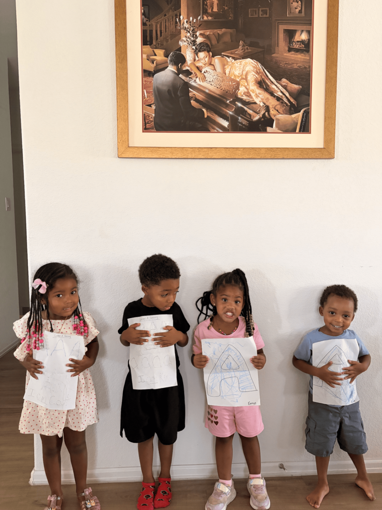 Four Little Disciples students proudly displaying their completed Letter A tracing work