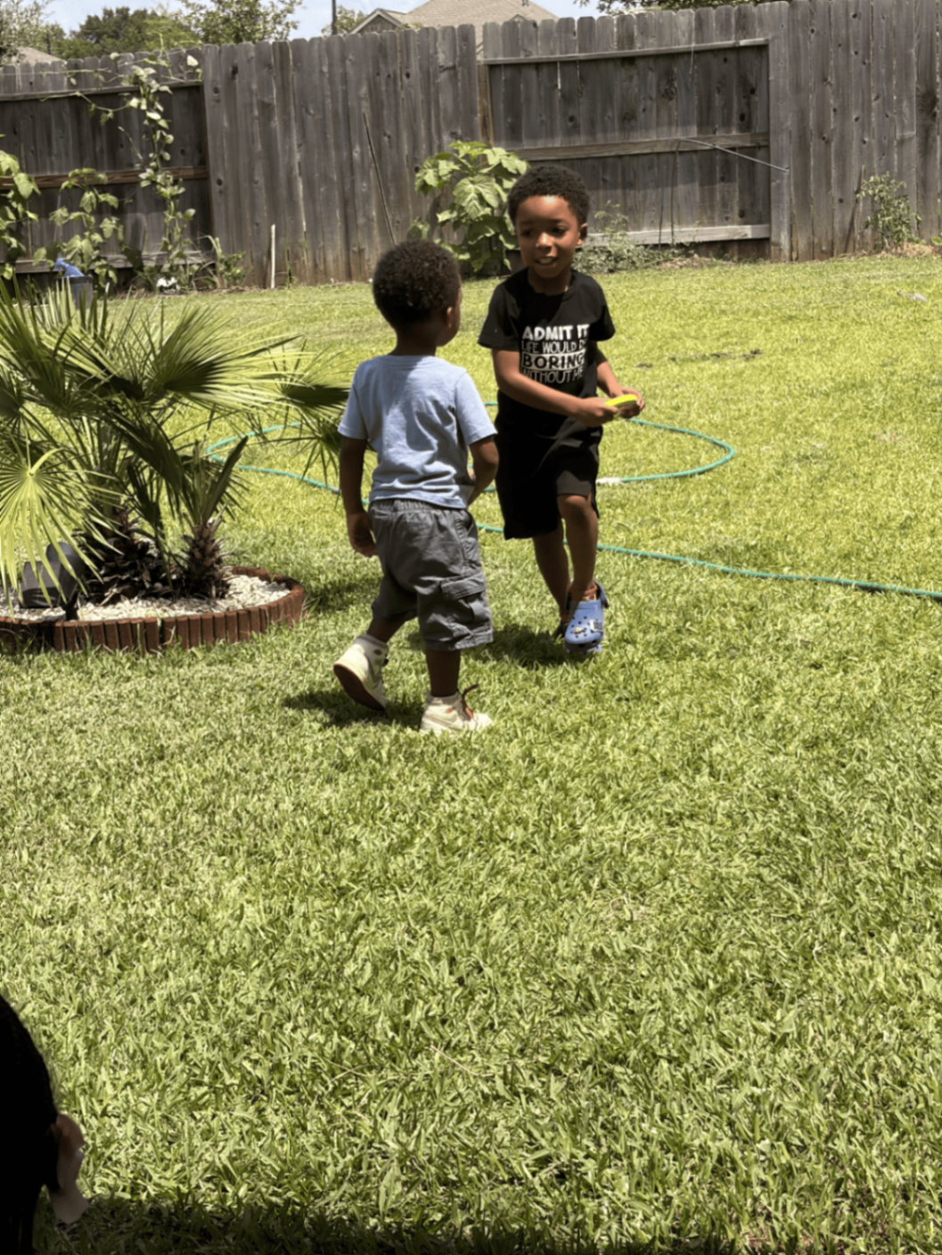 Two young campers running and playing a hula hoop game outdoors in the summer sunshine