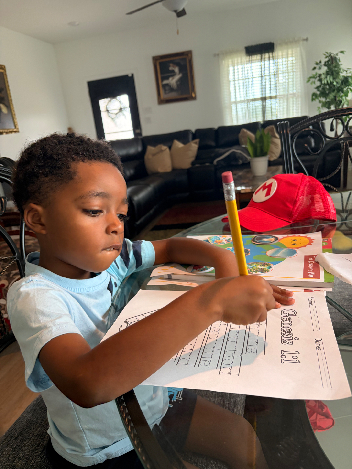 A young student tracing Genesis 1:1 on a handwriting worksheet